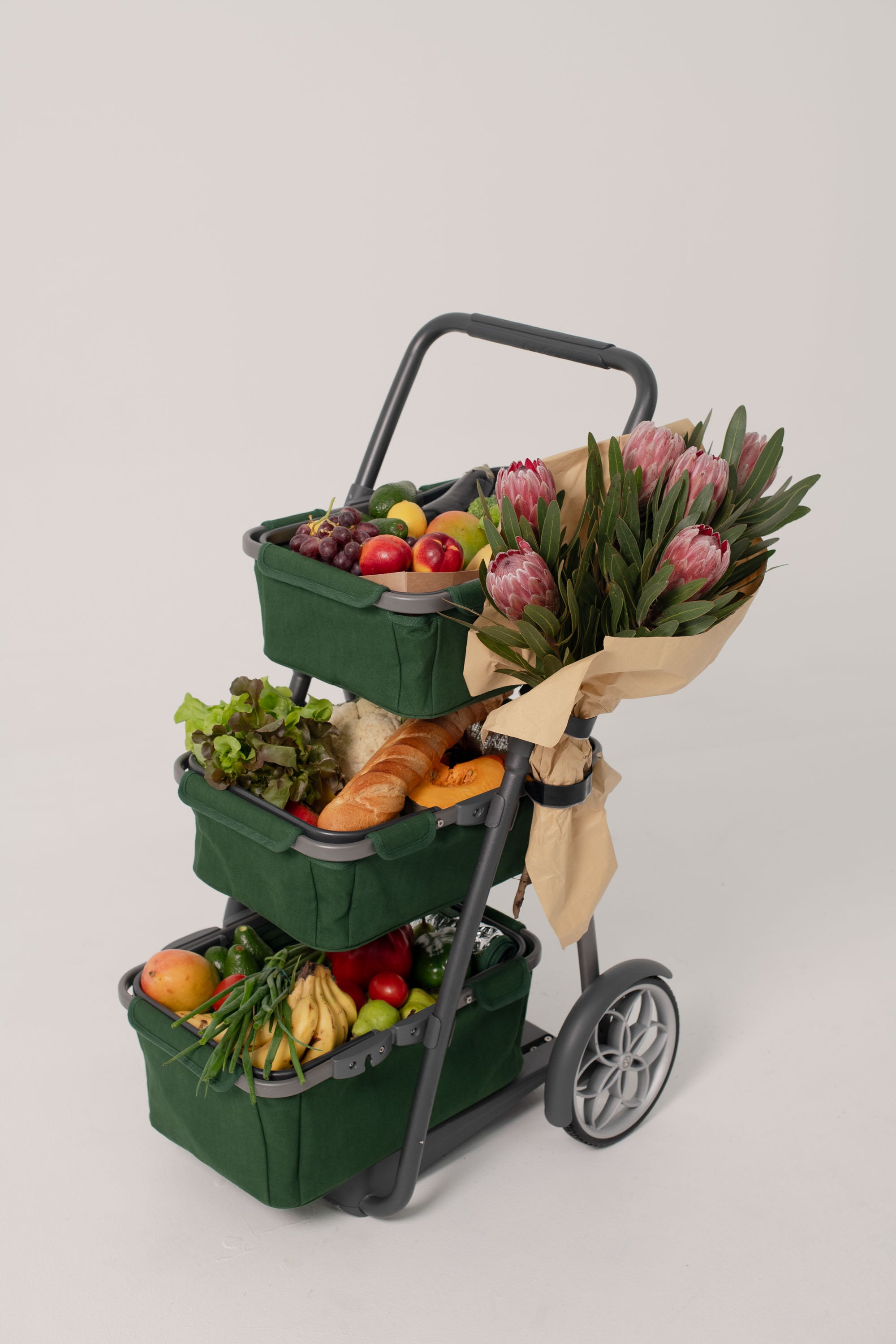 Green marketday cart with 3 tiers of storage and flowers attached to the side. The cart is fully loaded with fruit and vegetables